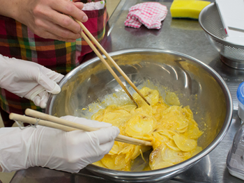 「ポテトオムレツ」作り。ジャガイモと玉ねぎをスライサーで薄切りにし、透き通るまでよく炒めます。炒めた物は卵液に加えてよく混ぜ合わせます。